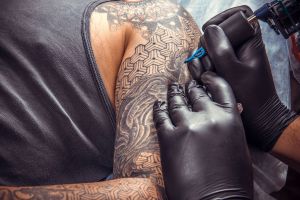 Καλλιτέχνης χτυπά τατουάζ στο χέρι άνδρα