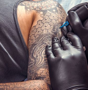 Καλλιτέχνης χτυπά τατουάζ στο χέρι άνδρα