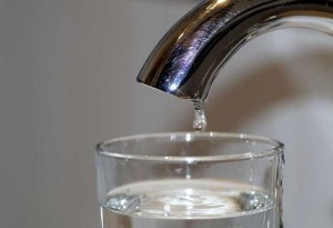 Μια σταγόνα από βρύση στάζει σε ποτήρι με νερό