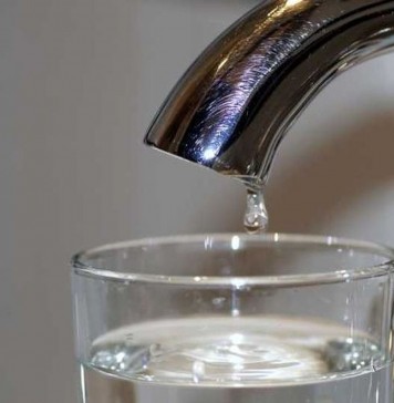 Μια σταγόνα από βρύση στάζει σε ποτήρι με νερό