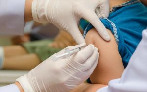 Νοσηλευτής εμβολιάζει ένα παιδί στον ώμο
