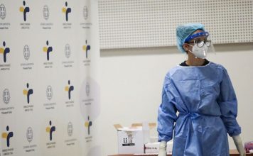 Νοσηλευτής με μπλε στολή και μάσκα σε κέντρο εμβολιασμού