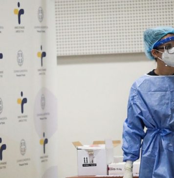 Νοσηλευτής με μπλε στολή και μάσκα σε κέντρο εμβολιασμού