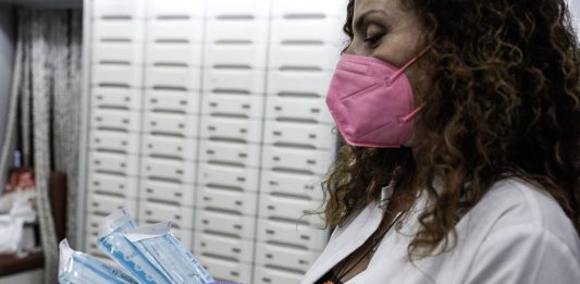 Φαρμακοποιός με μάσκα κρατά rapid tests