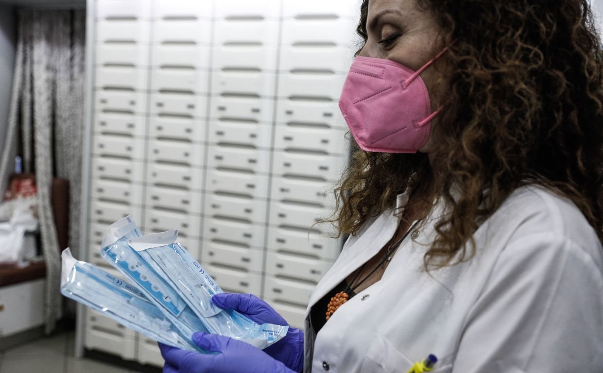 Φαρμακοποιός με μάσκα κρατά rapid tests