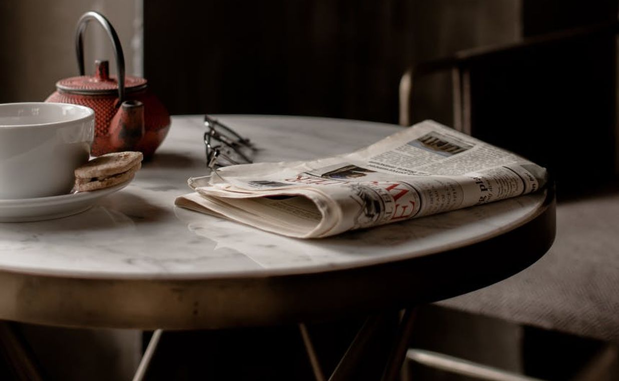 Εφημερίδα πάνω σε τραπέζι και φλυτζάνι καφέ
