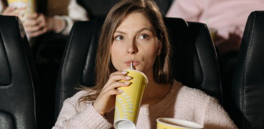 Νεαρή κοπέλλα παρακολουθει ταινίας σε αίθουσα κινηματογράφου