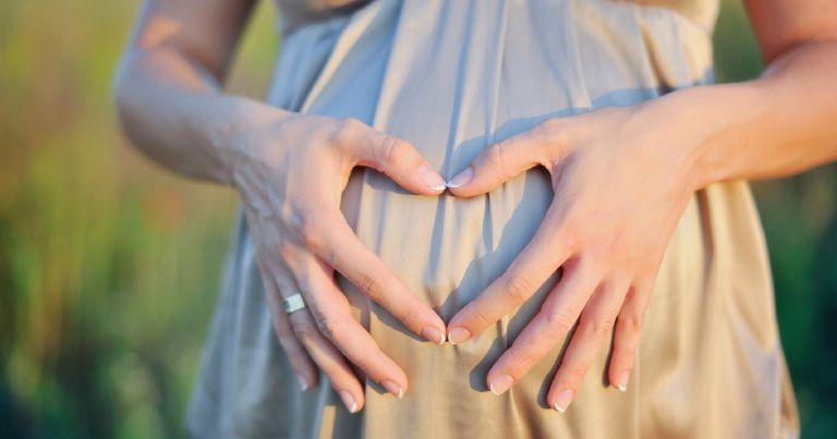 έγκυος γυναίκα σχηματίζει καρδιά πάνω στην κοιλιά της