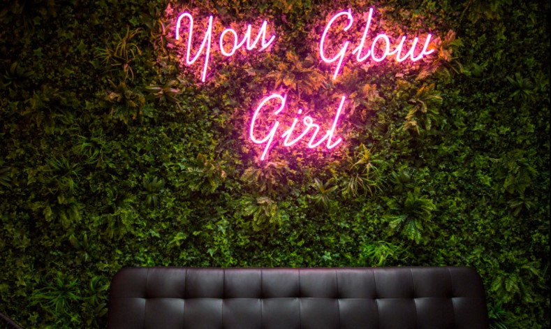 τοίχος με γρασίδι και φωτεινή επιγραφή you glow girl