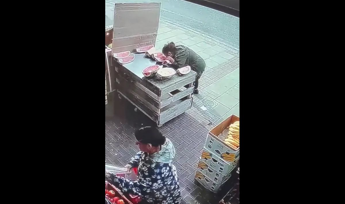 Γυναίκα δαγκώνει καρπούζι έξω από μανάβικο