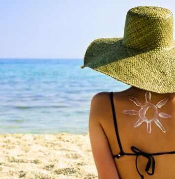 κοπέλα με ζωγραφισμένο ήλιο από αντιηλιακό στην πλάτη της