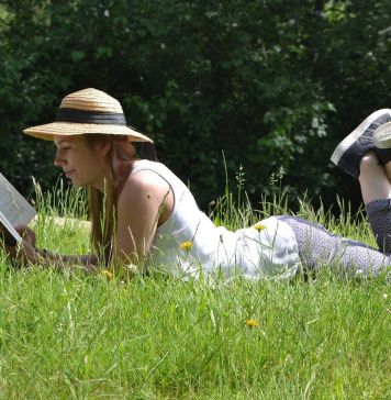 Γυναικα ξαπλωμένη στο χορτάρι στην εξοχή διαβάζει βιβλίο