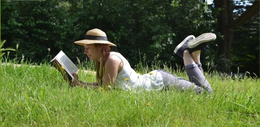 Γυναικα ξαπλωμένη στο χορτάρι στην εξοχή διαβάζει βιβλίο