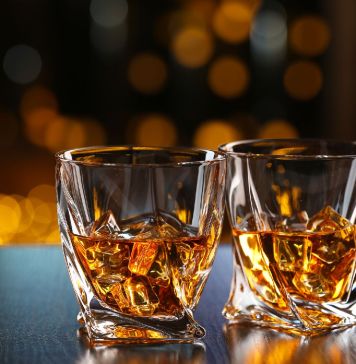 Glasses of whiskey on bar background