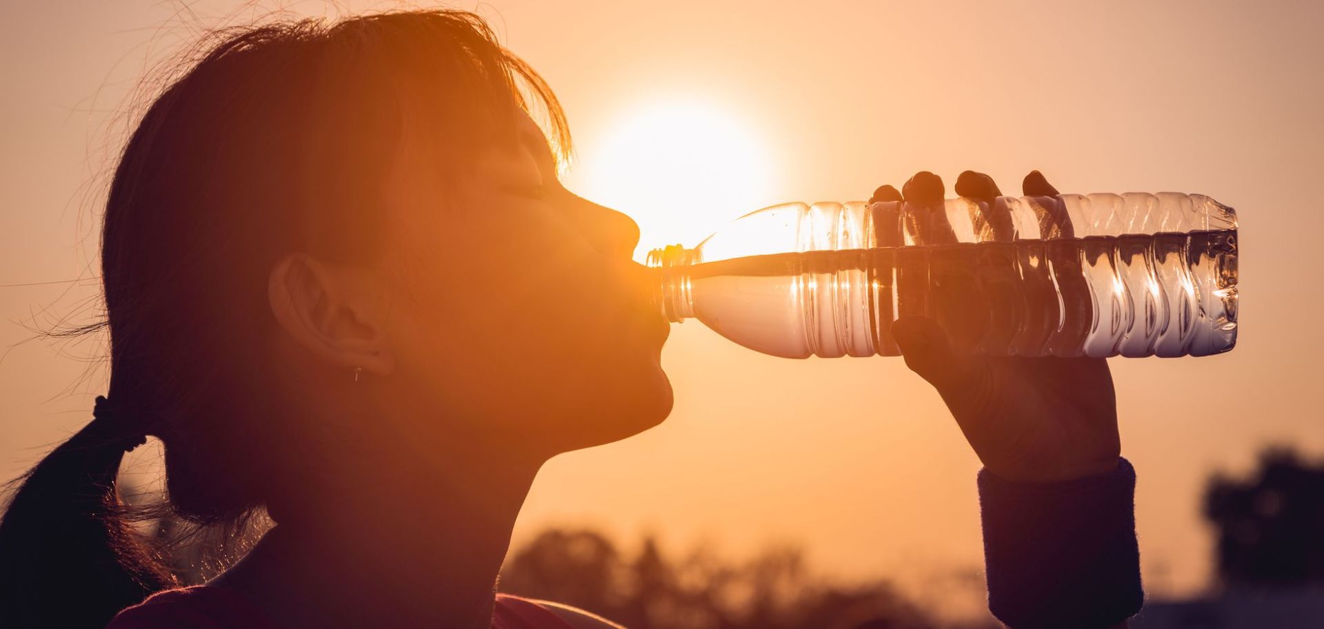 Κοπέλα πινει νερο απο μπουκαλι κάτω από τον καυτό ήλιο