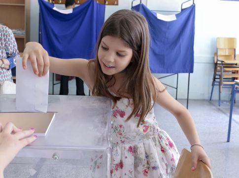Χαριτωμένο κοριτσάκι ρίχνει το ψηφοδέλτιο στη κάλπη