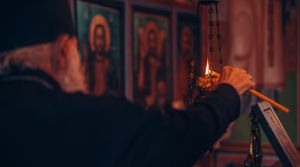 Ιερέας ανάβει κερί μέσα στην εκκλησία