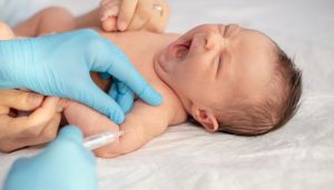 Pediatrician vaccinating newborn baby at shoulder.