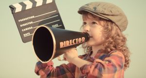 Kid holding clapper board against summer sky background. Cinema concept