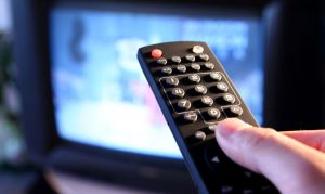 Ένα χέρι κρατά τηλεκοντρόλ τηλεόρασης και αλλάζει κανάλι