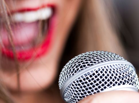 Γυναίκα καλλιτέχνης τραγουδα μπροστά σε ένα μικρόφωνο