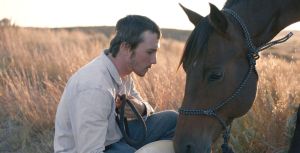 Ο Μπράντι Τζάντρο και το άλογο του κοιτάζονται με τα κεφάλια τους κοντά με φόντο ένα λιβάδι