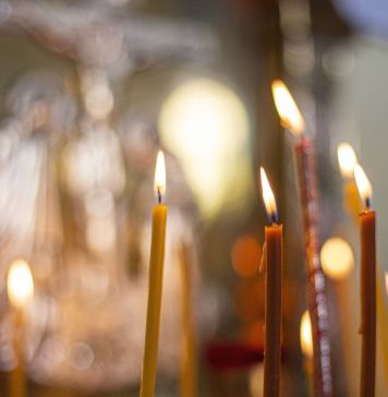 Κεριά απο κοντά μέσα σε εκκλησία και στο φόντο εκλησιαστικά εικονίσματας