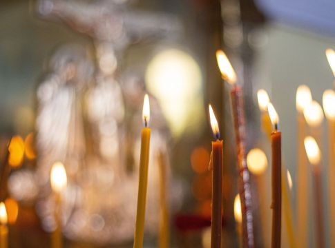Κεριά απο κοντά μέσα σε εκκλησία και στο φόντο εκλησιαστικά εικονίσματας