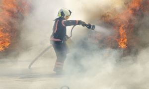 Πυροσβέστης ρίχνει με τη μάνικα νερό σε φωτιά που καίει