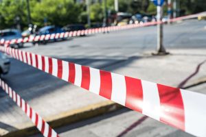 κόκκινη λευκή περιφραγμένη ταινία ασφαλείας σε δρόμο με σταθμευμένα αυτοκίνητα στο βάθος